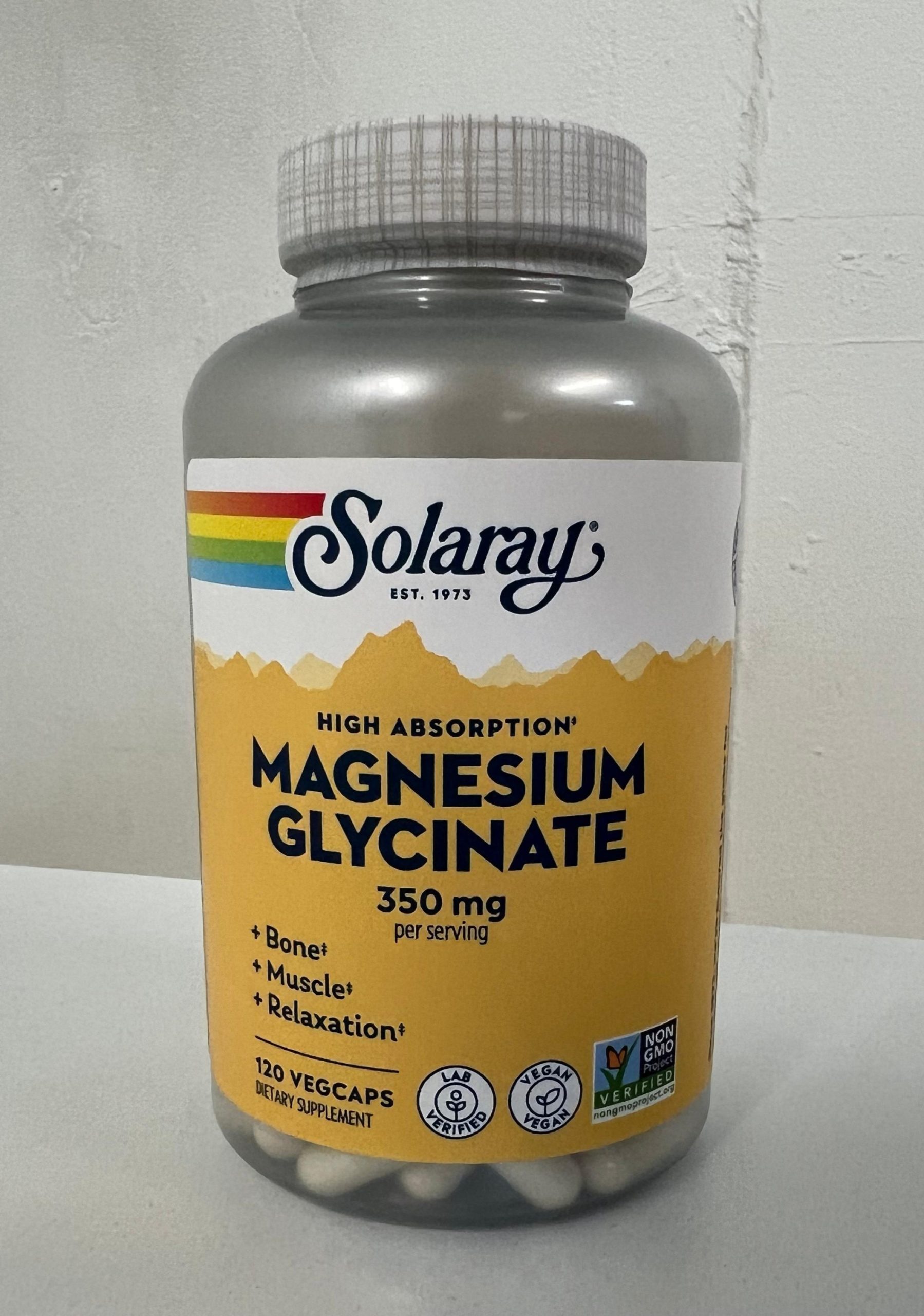 A bottle of Solaray High Absorption Magnesium Glycinate dietary supplement standing upright against a light background. The label is yellow and white with the Solaray rainbow logo at the top. The front reads “Magnesium Glycinate 350 mg per serving” with benefits listed as bone, muscle, and relaxation support. The bottle contains 120 vegan capsules and features vegan, lab verified, and non-GMO verified icons.